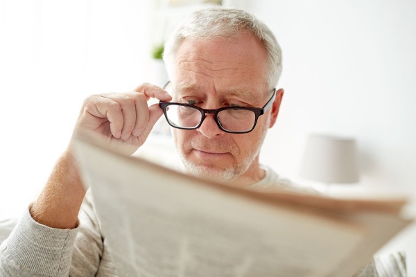 Man struggling to read newspaper