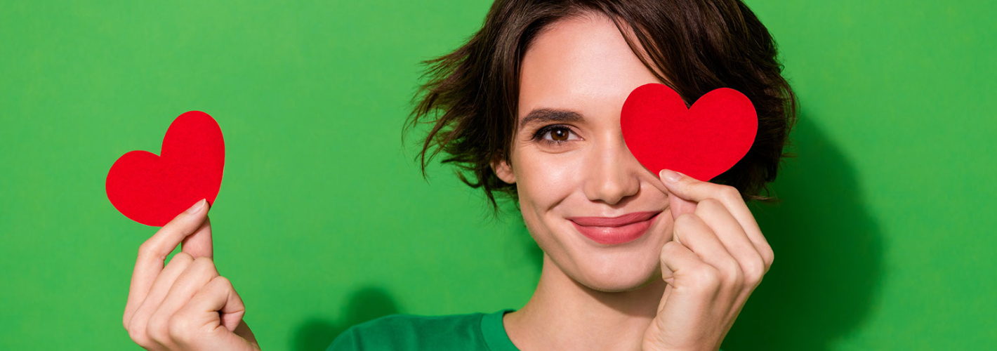 girl holding heart cutout in front of eye